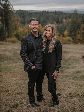 Dr. Tony Rhodes standing with his arm around his wife in the woods during a photoshoot