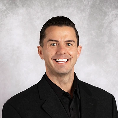 Tony Rhodes smiling in a black suit.